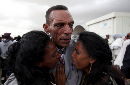 Addisalem Hadgu, reacts as he embraces his daughters, after meeting them for the first time in eighteen years, at Asmara International Airport after Ethiopian Airlines ET314 flight arrived in Asmara, Eritrea July 18, 2018.