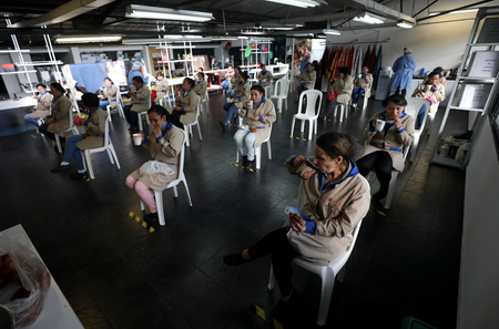 Employees of the leather manufacturer Mario Hernandez take a snack break at distance from each other amid the new coronavirus in Bogota, Colombia, Friday, May 15, 2020. Mario Hernandez is a company that meets social distancing and general health care requirements, allowing it to remain open amid the COVID-19 pandemic and lockdown. (AP Photo/Fernando Vergara)
