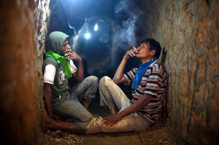 Palestinian tunnel workers smoke cigarettes as they rest inside a smuggling tunnel flooded by Egyptian security forces, beneath the Gaza-Egypt border in the southern Gaza Strip September 10, 2013. Egyptian security forces have stepped up a crackdown campaign on smuggling tunnels on the border between Egypt and Gaza Strip since last July, Hamas officials said.