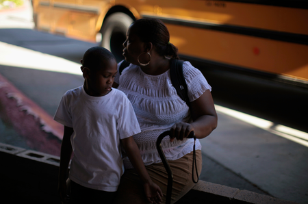 Black mother and son in front of school bus