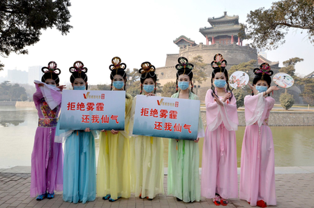 Members of a local short film club wearing masks and dressed in costumes of Chinese fairies pose for photographs with placards which read &quot;Say no to smog, return to me fairyism&quot;, during an event to raise awareness of air pollution, at a park in Handan, Hebei province