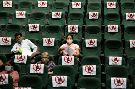 People wait after receiving their vaccine in a converted auditorium in Ahmedabad, India