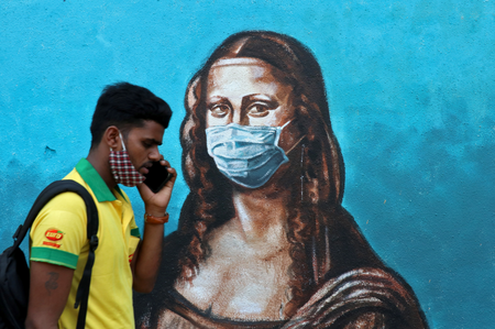 A man walks past a mural depicting the &quot;Mona Lisa&quot; wearing a face mask amidst the spread of the coronavirus disease (COVID-19), in Mumbai