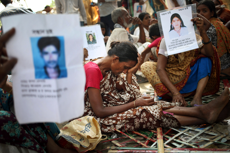 A woman grieves while others hold up pictures of their missing relatives.