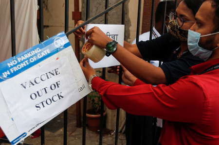 FILE PHOTO: Health workers attach a notice on the shortage of COVID-19 vaccine supplies at a vaccination centre in Mumbai