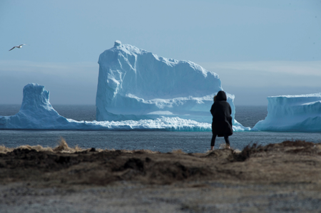 A resident views the first iceberg of the season as it passes the South Shore, also known as &quot;Iceberg Alley&quot;, near Ferryland Newfoundland, Canada April 16, 2017.