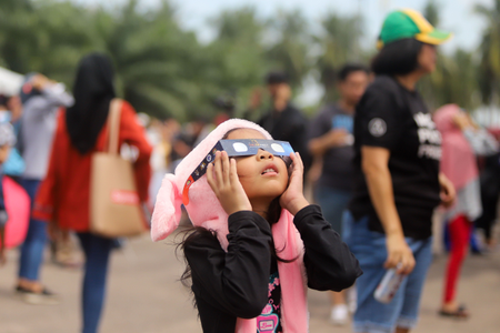 A young girl in Malaysia stares up at the eclipse