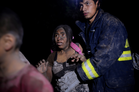 A rescue worker helps a woman covered with ash after Fuego volcano erupted violently in El Rodeo, Guatemala June 3, 2018. REUTERS/Fabricio Alonzo - RC1936B8FE70