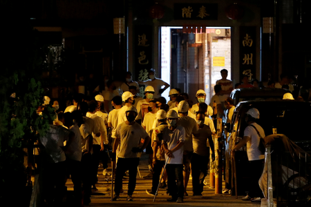 Men in white T-shirts and carrying poles are seen in Yuen Long after attacking anti-extradition bill demonstrators at a train station in Hong Kong, China, July 22, 2019.