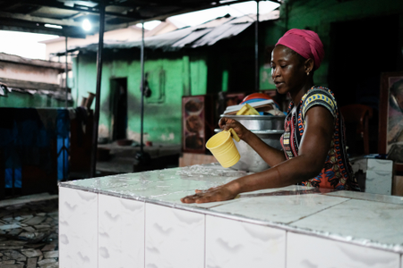 A woman wiping down the serving counter at the end of the day at a popular chop bar at Atwemonom.