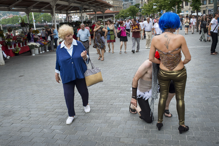 A woman walks past participants at a gay pride in Bilbao