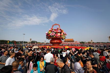 Visitors gather near a giant basket decorated with replicas of flowers and fruits on display at Tiananmen Square on China&#039;s National Day in Beijing, Sunday, Oct. 1, 2017. Hundreds of thousands foreign and domestic tourists flock to the square to celebrate the 68th National Day and the Mid-Autumn Festival over the week-long holidays.