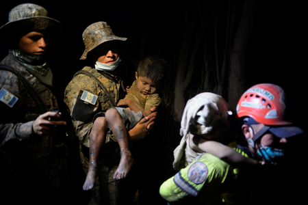 A soldier takes a rescued child covered with ash to a hospital after Fuego volcano erupted violently in El Rodeo, Guatemala June 3, 2018.