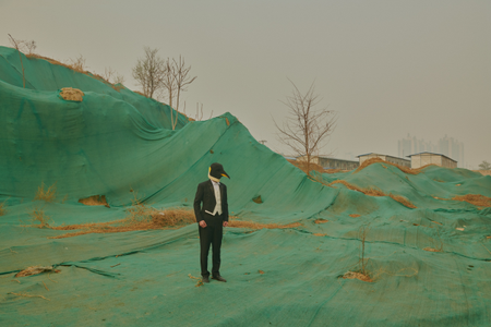 This picture showing the penguin man standing ono a construction site shows how development is constant in Beijing, said Xu. The green sheets covering the mounds of sand resemble man-made mountains.