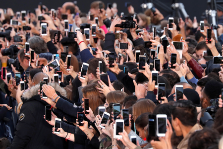 Dozens of people use their smartphone to take photos of the L&#039;Oreal fashion show on the Champs Elysees avenue in 2017