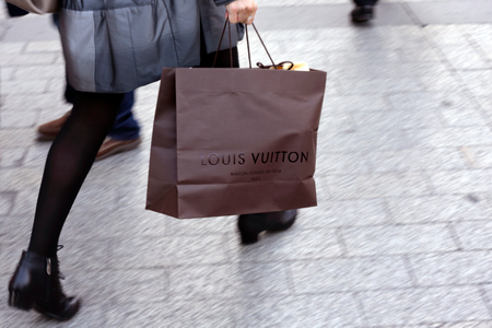 A woman walks with a Louis Vuitton shopping bag as she leaves a Louis Vuitton store in Paris.