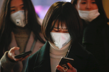 Women wearing face masks wait for the bu