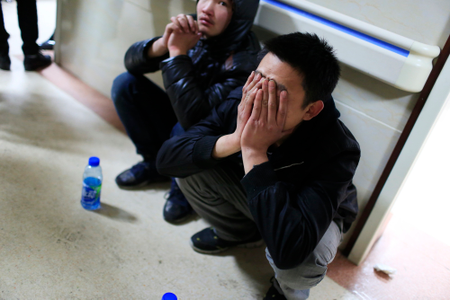 A friend of a victim covers his face as he waits outside a hospital where injured people of a stampede incident are treated, in Shanghai