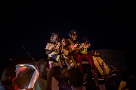 Children from the town join Ami atop a car during her processional around town; young men blasted her music from loudspeakers, announcing her arrival on May 20, 2017 in Macina, Mali.