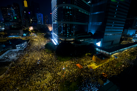 Thousands of protesters attend a rally outside the government headquarters in Hong Kong as riot police stand guard September 27, 2014.