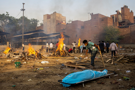 A man prepares a funeral pyre to cremate the body of a person, who died due to the coronavirus disease (COVID-19), at a crematorium ground in New Delhi