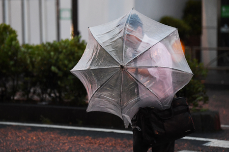 A man with an umbrella crosses a street early morning under the rain as a typhoon hits Tokyo on Sept. 9, 2019.