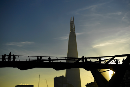 Commuters make their way across the Millennium Bridge as the sun rises over London