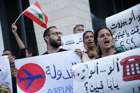 Demonstrators carry banners and a Lebanese flag as they protest outside the Touch telecommunications building in Beirut, Lebanon November 5, 2019.