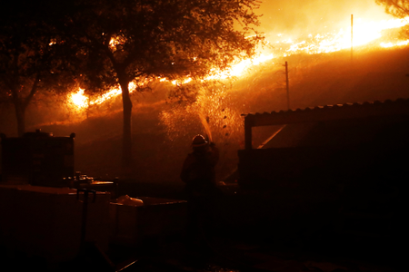 A firefighter defends a structure against approaching flames while in Geyserville.