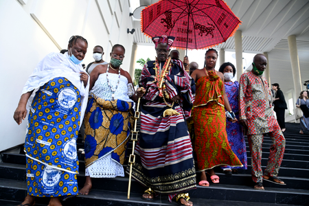 O governante tradicional de Abomey-Calavi, Kpoton Avounbe, Allodji III, (C) e sua família chegam para participar da abertura de uma exposição simbólica para exibir artefatos saqueados por soldados coloniais franceses que retornaram ao país na presidência em Cotonou em 19 de fevereiro de 2022