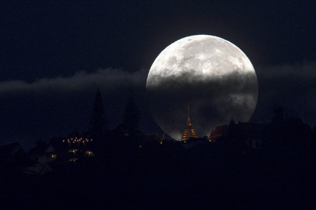 The supermoon is partly covered by clouds as it sets behind Wat Phrathat Doi Suthep in the northern capital of Chiang Mai, Thailand, November 15, 2016.