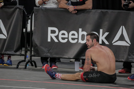 A CrossFit athlete takes a rest in front of a Reebok sign
