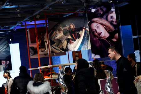 Shoppers walk past images of pop star Beyonce at an Adidas store