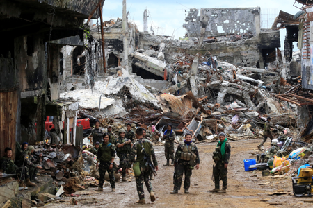 Government soldiers stand in front of damaged houses and buildings in Marawi city, Philippines, October 25, 2017.