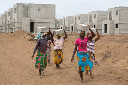Women carry bricks at the construction site of real estate company Sipim in Grand Bassam, Ivory Coast. They are paid 25 West African francs (about $0.04) for each brick.