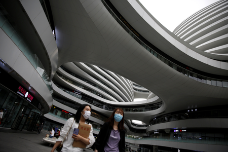 People wearing face masks walk at the Galaxy SOHO office and commercial buildings, following the novel coronavirus disease (COVID-19) outbreak, in Beijing