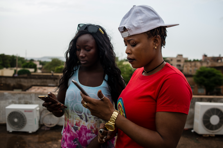 Ami and her friend, also a musician, check their phones after uploading to Instagram on May 22, 2017 in Bamako, Mali.