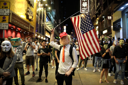 A person dressed as President Donald Trump waves an American flag as they stand on a street in Hong Kong on Oct. 31.