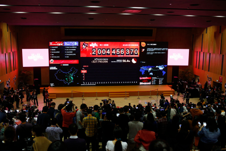 Employees and journalists take pictures and videos of a giant electronic board showing the online transaction value on Alipay,
