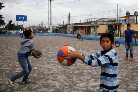 Children play at a basketball court covered with ash after Guatemala&#039;s Fuego volcano erupted violently, in Guatemala City, Guatemala June 3, 2018. REUTERS/ Luis Echeverria