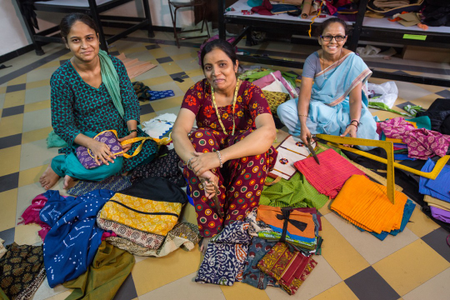 Ahmedabad, India: Rehat Rangrez (L), Noorjahan Makrani (C), and Sangeeta Parmar (R) create handcrafted bags at the Self-Employed Women&#039;s Assocation (SEWA) Artisan House. The house was opened in 2014 to support women artisans in the informal sector to continue their craft and increase their earning power. The Artisan House also sells their products, eliminating the issue of a middleman cutting into the women&#039;s small incomes.