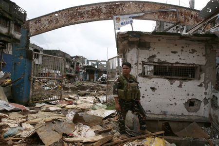 A government soldier stands guard in front of damaged buildings in Marawi city, Philippines October 25, 2017.