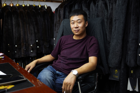 Wenyuan Wang sits at the back of his fur coat store in Khorgos ICBC.