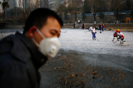 A Chinese man wears a mask while watching people play ice hockey on a frozen river while haze hangs over downtown Beijing city, China, 16 December 2016. Officials in China&#039;s capital Beijing issued a red alert for air pollution, which is expected to last until 21 December. EPA/WU HONG