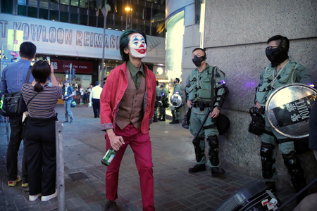 A man in a Halloween costume walks past police officers in riot gear in Hong Kong on Oct. 31.