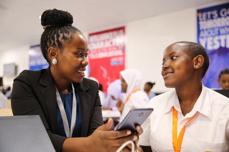 Carolyne Ekyarisiima inspecting the mobile app developed by one of the young coders at the Entrepreneurship Summit.