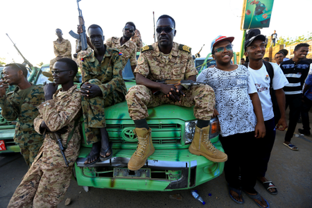 Sudanese boys pose for a photo with Sudanese military personnel, positioned near a bridge gate, during a sit-in protest outside the Defence Ministry in Khartoum, Sudan April 15, 2019.
