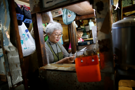 75-year-old Tai Yamaguchi, who has been tending her family&#039;s fish shop for more than 50 years, works inside an accounting booth at her shop at the Tsukiji fish market in Tokyo, Japan, September 25, 2018. REUTERS/Issei Kato - RC13F57570E0
