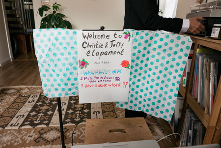 This is a photo of the backdrop people tuning into the livestream were presented. It says: Welcome to Christie and Jeff&#039;s elopement. Wash your hands. Mute your audio until we toast. Have a drink to toast.