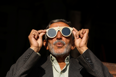A man uses a pair of welder glasses to observe a solar eclipse in Peshawar, Pakistan